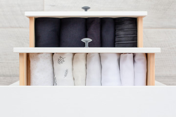 two open chest shelves with clothes in black and white stacked in neat piles