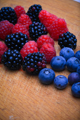 Background of fresh fruits and berries. Ripe blackberries, blueberries, plums, raspberries. Mix berries and fruits. Top view. Background berries and fruits. Black-blue and red food.