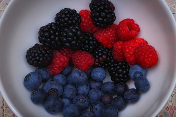 Background of fresh fruits and berries. Ripe blackberries, blueberries, plums, raspberries. Mix berries and fruits. Top view. Background berries and fruits. Black-blue and red food.
