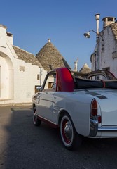 ALBEROBELLO, ITALY - AUGUST 27 2017: vintage old car parked through trullo buildings in Alberobello