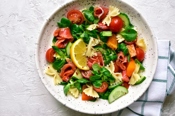 Pasta salad with vegetables and salted salmon. Top view with copy space.