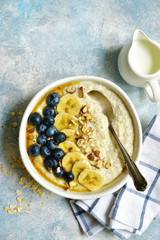 Oatmeal porridge with banana, fresh blueberry and nuts - healthy breakfast. Top view with copy space.