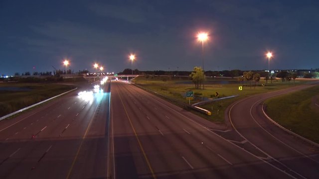Traffic Speeds North and South on the Florida Turnpike in a 4K Time-Lapse at Sample Road in Pompano Beach from the Overpass Bridge at Night with Some Vehicles Curving to the Right on the Off-Ramp