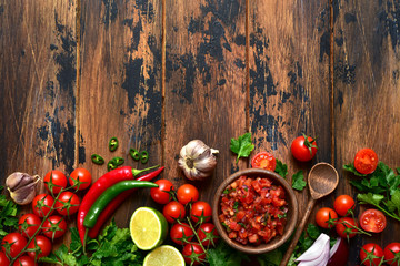Tomato salsa (salsa roja) - traditional mexican sauce  with ingredients for making. Top view with copy space.