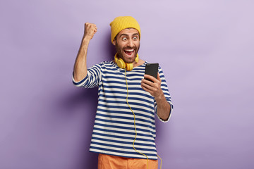 Triumphing happy guy raises clenched fist, celebrates winning lottery, gets message of confirming...