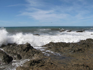 Ocean with white water coming onto dark rocks