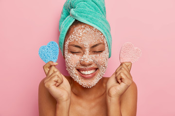 Close up image of delighted healthy woman laughs sincerely, keeps eyes closed, shows white perfect...