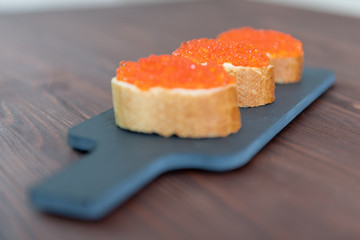 Set of three sandwiches with red caviar on the grey stone background