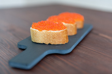 Set of three sandwiches with red caviar on the grey stone background