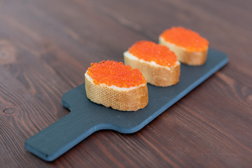 Set of three sandwiches with red caviar on the grey stone background