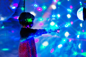 The child reaches for the light. Girl at a party with disco. Laser show at a children's party. Happy childhood.