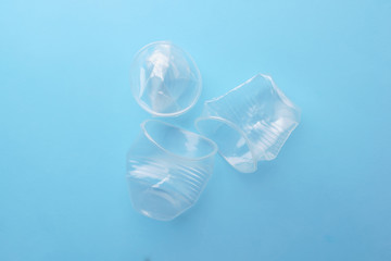 Crushed plastic cups on blue background. Garbage, environmental pollution, recycling and zero waste...