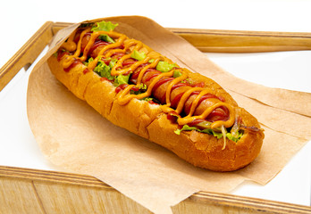 Hot dog with salad and cucumbers with tomato ketchup and mustard on white background. Tasty and beautiful fast food on a light back.