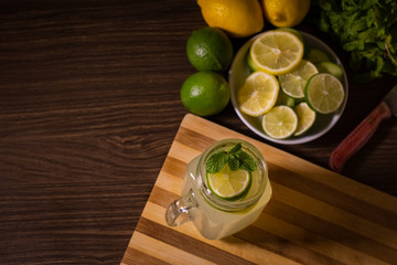 Lemonade with mint in a glass on a kitchen table.- Lemon and lime juice with mint leaves.