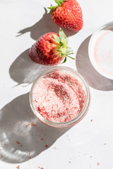 A strawberry lemonade drink in a can like glass standing on a marble countertop. Direct sunlight from the aide casting a hard shadow on the countertop. Bottom is whole strawberry with strawberry sugar - 289754606