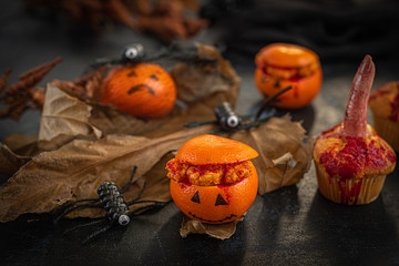 halloween oranges, muffin with bloody finger, spiders, bloody fingers and oranges on a dark background, moody, spooky, scary, decoration idea