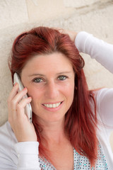 Cute smiling redheaded woman making a call with her cell phone