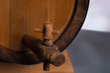 Wooden barrel with tap on a black mirror. White background behind.