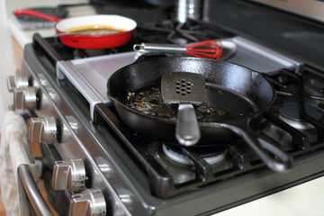 Used skillets resting on the stove top in a kitchen.