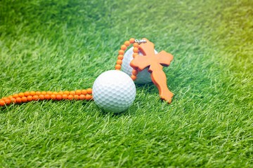 Christian cross and golf ball are on green grass