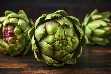 Fototapeta premium Fresh raw organically grown artichoke flower buds on wooden table