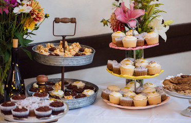 dessert table at wedding, gourmet cupcakes at an event, assortment of cup cakes on tiered platter, platter of baked goods