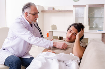 Obraz premium Old male doctor visiting young male patient
