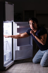 Man breaking diet at night near fridge