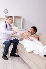 Obraz premium Old male doctor visiting young male patient