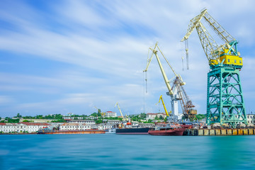 Fototapeta na wymiar Seascape with the coastline of the port and large floating cranes.