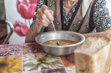 The old woman eats soup, charity food for the poor pensioners, social reform