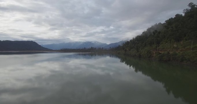 Aerial of Intact Lake Under Mountainous Hills And Cloudy Skyline. New Zealand West Coast Nature