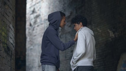 Black college student intimidating scared classmate hitting, teenage bullying