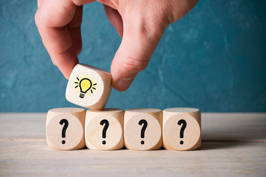 hand stacking cubes with lightbulb symbol on top of some with questionmarks