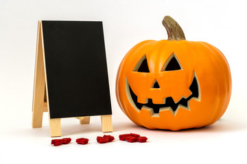 Happy plastic pumpkin with a blank chalkboard and licorice candy for office party