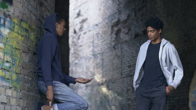 Black young criminal with bat demanding money on abandoned street, extortion