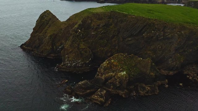 Aerial orbital of stunning cliffs and rock shelters near The Silver Strand beach in Ireland