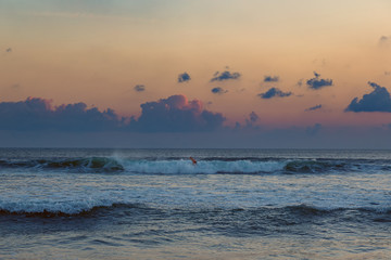 Surfing man at sunset in Seminyak, Bali