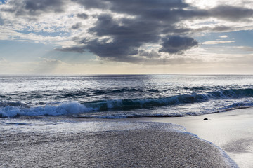 Evening view with sun shining throug clouds at Makua beach, Oahu, Hawaii