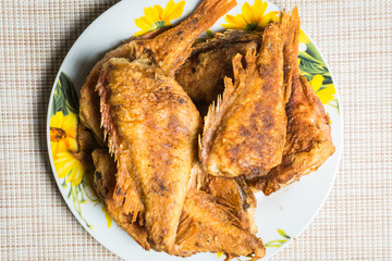 Cooked fried sea bass in plate on kitchen table.