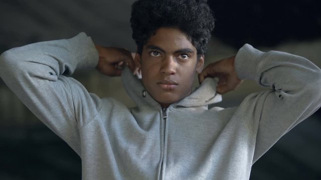 Black young criminal putting on hood looking around going to commit crime, risk