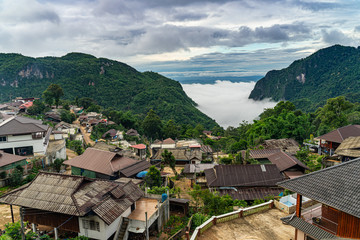 Fototapeta premium Misty mountain in the morning rainy season over small village at Doi Pha Hee countryside, Chiang Rai Thailand