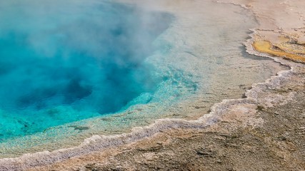 A close-up view of the steaming, turquoise Silex Spring and the rough crust surrounding its edges. Yellowstone.