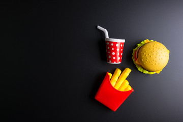 Plastic burger, French fries Fast food on black background. Children's toy. Concept of harmful artificial food. Plastic. Not organic. Not useful.