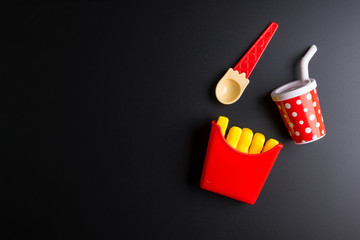 Plastic burger, French fries Fast food on black background. Children's toy. Concept of harmful artificial food. Plastic. Not organic. Not useful.