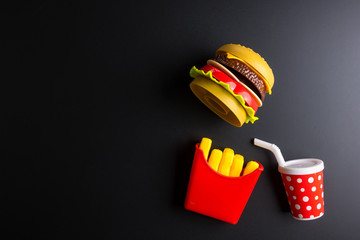 Plastic burger, French fries Fast food on black background. Children's toy. Concept of harmful artificial food. Plastic. Not organic. Not useful.
