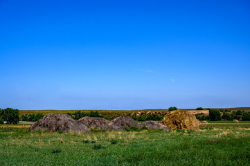 Obraz premium Hay stack on grass field on sloped hillside