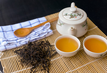 Top view of Chinese hot tea in a white cup with tea leaf and wooden spoon on the table