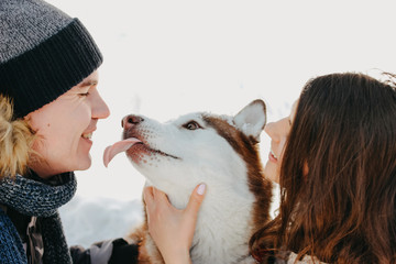 The happy couple with dog haski at forest nature park in the cold season. Travel adventure love story