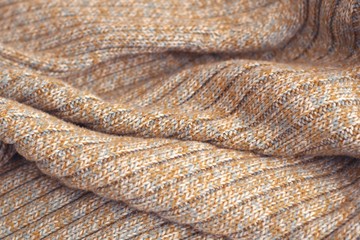Mottled beige knitted sweater. Texture detail close up.